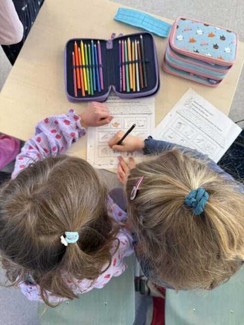 Kinder, die an einem Arbeitsblatt arbeiten, von oben fotografiert